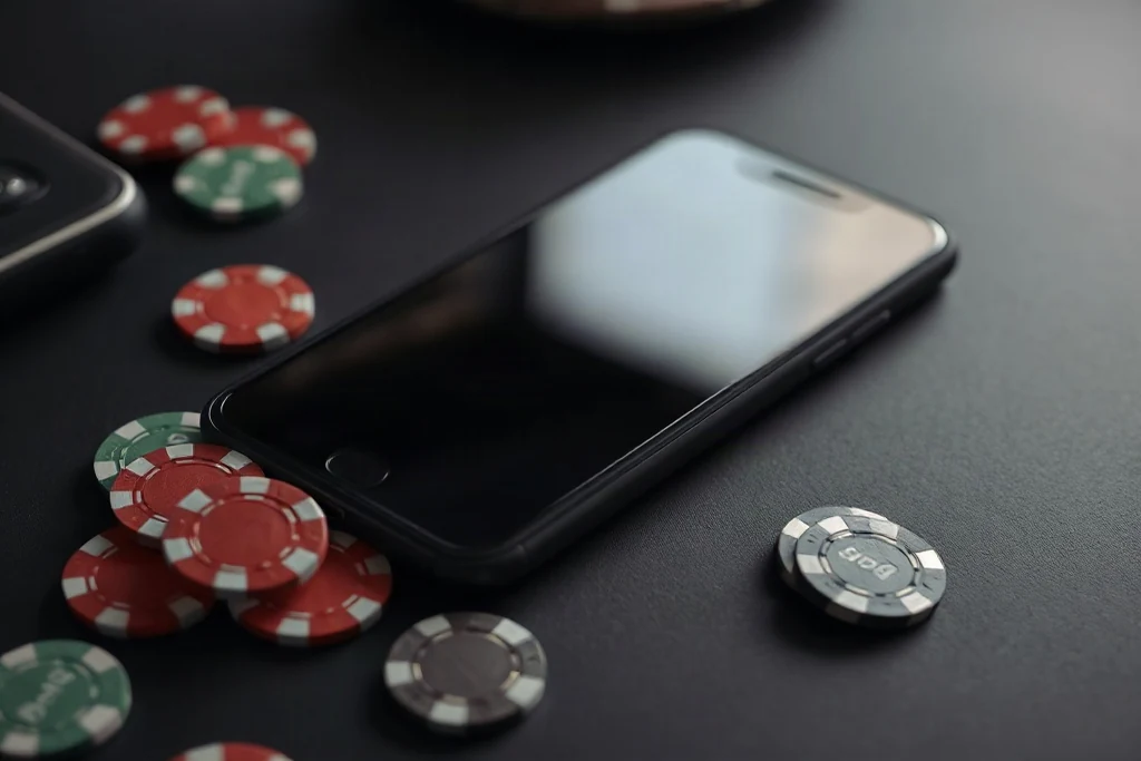 Smartphone com tela apagada ao lado de fichas de pôquer sobre mesa